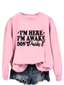 Detail of pink long-sleeve sweatshirt featuring bold black I'M HERE I'M AWAKE slogan print - Pink (Black Text)