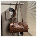Detail of vintage brown cylinder bag showing shiny PU leather texture and adjustable strap - Tan
