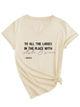 Dettaglio della t-shirt beige con scollo a V, stampa frontale e nodo alla moda sull'orlo - S / Sabbia (Carattere Nero)