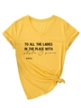 Dettaglio flat lay della maglietta gialla con scollo a V, nodo alla moda e stampa grafica - S / Giallo (Carattere Nero)
