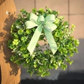 Detail von St. Patrick's Day Kleekranz mit grün gestreifter Schleife in der Hand - Mit Schleife / 40CM
