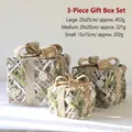 Lot de trois boîtes cadeau de Noël en rotin blanc avec nœuds et branches de pin enneigé - Combinaison de Boîtes Cadeaux Grande Moyenne Petite