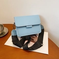 Minimalist light blue square crossbody bag with wide black nylon strap on table - Blue
