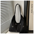 Detail view of flower cutout patterns on black suede shoulder bag with natural light shadow - Black