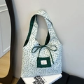 Stofftasche mit Blumenmuster, grünem Karomuster und Schleifenband auf einem Magazin - Grün Blumenmuster
