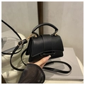 Detalle de un mini bolso bandolera de cuero negro con dos hebillas doradas y asa de mano - Negro