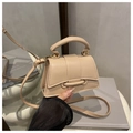 Detalle de un mini bolso bandolera beige en piel sintética lisa sobre un soporte de exhibición - Caqui