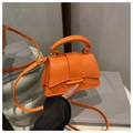 Detalle de un mini bolso naranja vibrante con asa cilíndrica y cierre de solapa elegante - Naranja