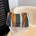Borsa tote in tela a righe con manici in pelle arancione su sedia minimalista - Blu