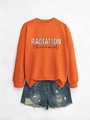 Macro shot of orange crewneck sweatshirt featuring colorful Radiation Therapist graphic print - Orange Sweatshirt (Black Text Graphic)