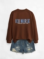 Close-up of ICU NURSE lettering on a dark brown crewneck sweatshirt and denim shorts - Coffee (White Print)