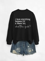 Flat lay of a black long sleeve sweatshirt with text and distressed denim shorts - Black Sweatshirt (White Font)