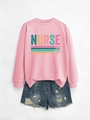 Close-up of pink nurse sweatshirt with caring strong text and ripped denim shorts - Pink