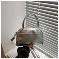 Detail of silver metallic handbag with dual handles and gold-toned metal hardware buckles - Silver