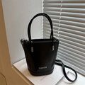 Sac seau noir minimaliste avec deux poignées et une bandoulière dans un décor moderne - Noir