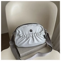 Detalle del bolsillo delantero plisado de un bolso bandolera gris claro con logo M metálico - Gris