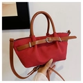 Dettaglio ravvicinato di una borsa tote in pelle rossa con texture opaca e manici marroni - Rosso