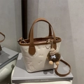 Chic cream and brown tote bag with embossed patterns and plush monster charm on books - White With Pendant