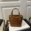 Tan embossed crossbody bucket bag with butterfly and puppy motifs on matte leather - Brown