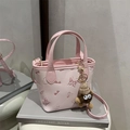 Pink embossed mini tote bag with playful patterns and a plush monster charm - Pink With Pendant