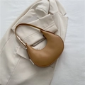 Minimalist caramel brown crescent shoulder bag with silver hardware on a cream blazer - Khaki