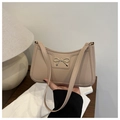 Primer plano detallado del bolso de media luna beige con accesorio metálico de lazo dorado - Caqui