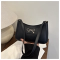 Detalle de bolso medialuna negro con lazo metálico plateado y textura de cuero mate - Negro