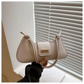 Close-up of cream-white leather shoulder bag featuring unique knotted strap and gold buckle - White