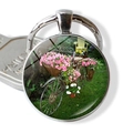 Vintage bicycle flower basket keychain with a round silver pendant and garden imagery - Landscape Bike and Pink White Potted Plants (JY007506-7)