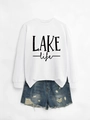 Flat lay of white crewneck sweatshirt with LAKE life text and distressed denim shorts - White Sweatshirt (Black Print)