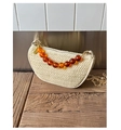 Detail view of woven saddle bag with amber beads and gold chain on wooden table - White