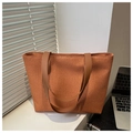 Dettaglio della borsa tote in paglia intrecciata con manici in pelle marrone su scrivania - Marrone