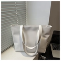 Dettaglio della borsa tote intrecciata bianca con motivi verticali su una scrivania sobria - Bianco