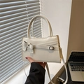 Chic cream white crossbody handbag with bow decoration and top handle in a lifestyle setting - White