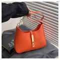 Détail du sac à main orange en cuir avec fermoir doré et bandoulière en chaîne chic - Orange