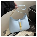Detailed shot of light blue crescent bag featuring golden bar buckle and metal chain strap - Blue