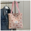 Detail der pinkfarbenen Cord-Einkaufstasche mit Kirschmuster und gewebtem Etikett - Rosa