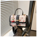 Detail van bedrukte leren crossbodytas met kersenpatroon en gouden gespsluiting - Zwart