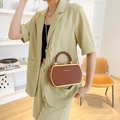 Brown hexagonal crossbody bag with metallic edges and woven handle on green suit - Brown