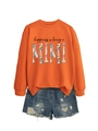 Detail of orange sweatshirt with floral Mimi print paired with distressed denim shorts - Orange (Black Text)
