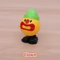 Wind-up clown walking toy in yellow finish with green star hat on wooden surface - Clown