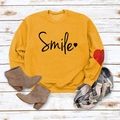 Ginger yellow Smile sweatshirt with heart print styled on a white wooden background - Yellow (Black Font)