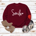 Flat lay of wine red sweatshirt with Smile print and heart patch embroidery on wood background - Wine Red (White Font)