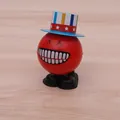 Wind-up jumping ball toy in red with star hat and black shoes on wooden table - Star Spangled Hat Smiley