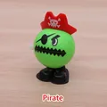 Wind-up pirate toy in green with red hat and eye patch on a wooden surface - Pirate With Red Hat
