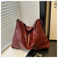 Detail of burgundy oil wax tote bag showing glossy texture and silver eyelets on straps - Red