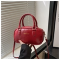Detail of red glossy bowling bag showing dual handles and detachable shoulder strap - Red