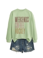 Detail of light green sweatshirt with Weekends Coffee Hockey text and ripped denim shorts - S / Olive Green