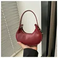 Detail of wine red leather crescent bag with elegant gold zipper and metal rivets - Red