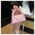 Detailed close-up of a pink trapezoid handbag featuring a gold geometric buckle - Pink